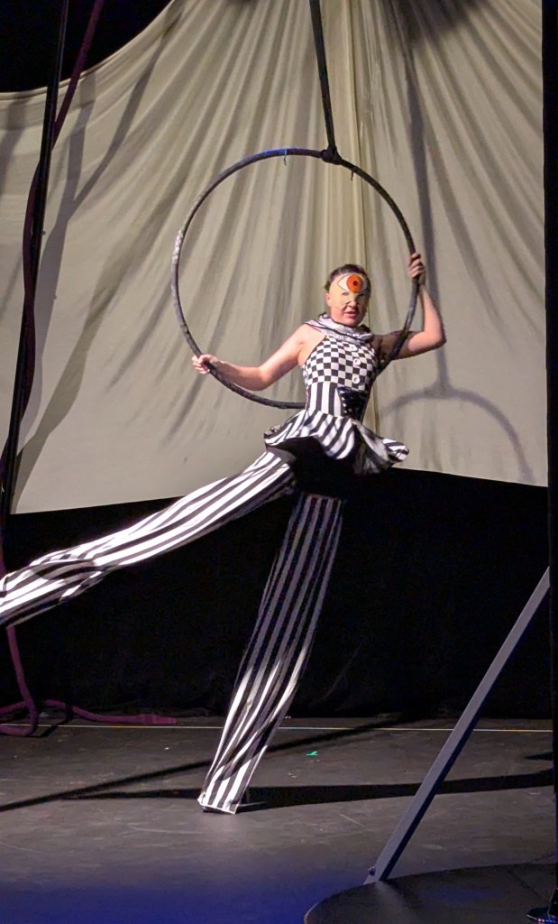 A dancer on stilts swinging around a lyar